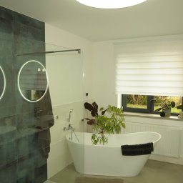fliesen-tech - Nowoczesna łazienka z wanną wolnostojącą, szklaną kabiną prysznicową i okrągłymi lustrami z podświetleniem LED. Minimalistyczny design, jasne kolory i roślina doniczkowa.
