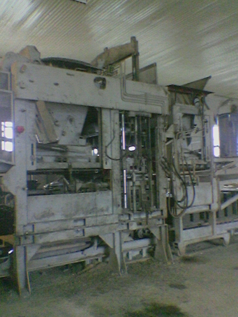 Wibroprasa Zenith, przemysłowa maszyna do produkcji kostki brukowej, widok z boku w hali produkcyjnej, metalowa konstrukcja z przewodami hydraulicznymi.