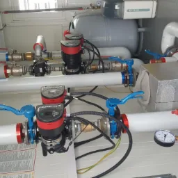 Węzeł cieplny z pompami obiegowymi Grundfos, zbiornikiem wyrównawczym Keller i kompletem rur z zaworami, zamontowany w kontenerze.