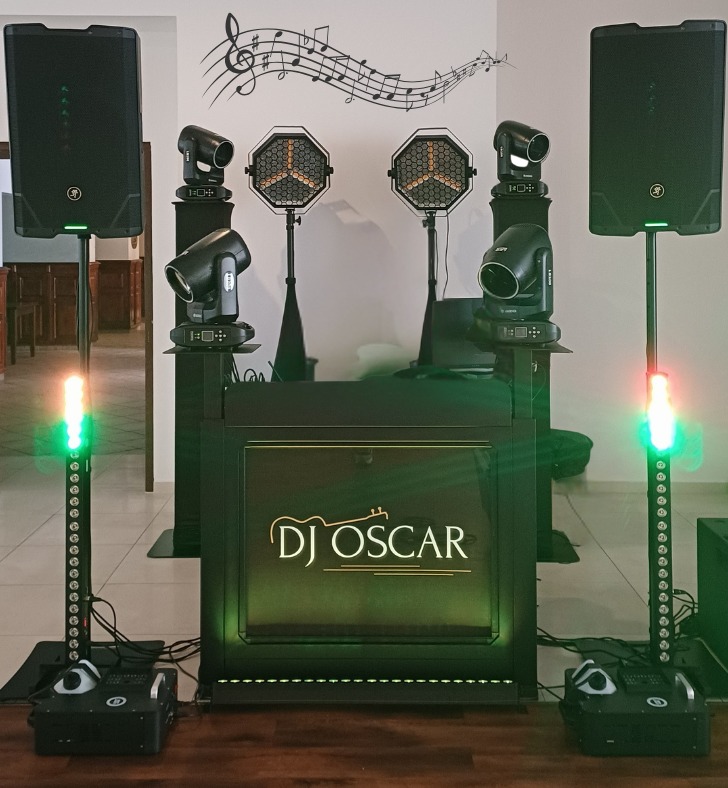 Profesjonalne nagłośnienie i oświetlenie DJ Oscar: kolumny głośnikowe, reflektory sceniczne i konsoleta DJ-ska z podświetlanym logo, gotowe do występu.