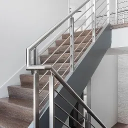 Nowoczesne schody drewniane z metalową balustradą ze stali nierdzewnej, minimalistyczny design.