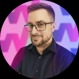 Portret mężczyzny w okularach z delikatnym uśmiechem na tle abstrakcyjnym z gradientem fioletu i różu.