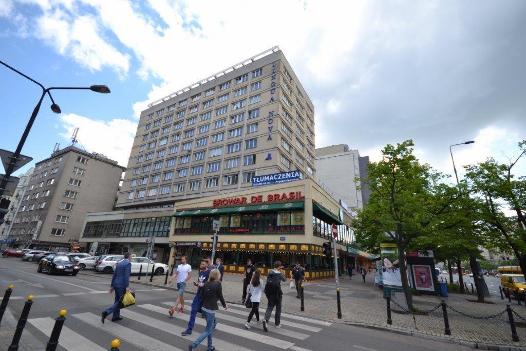 Budynek z szyldem 'Lingua Nova Tłumaczenia' nad restauracją 'Browar de Brasil', widok z ulicy z przechodzącymi pieszymi.