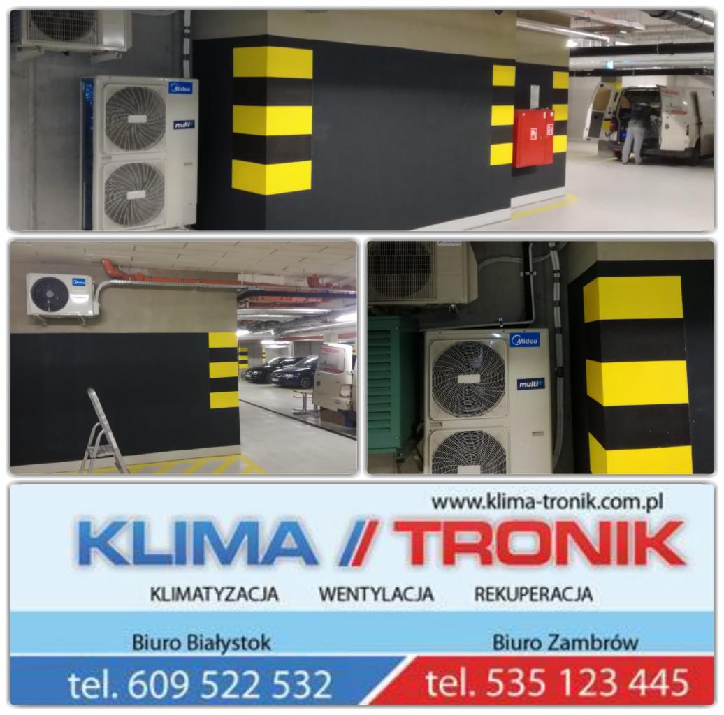 Klimatyzatory Midea Multi zainstalowane w podziemnym parkingu, widoczne żółto-czarne oznaczenia filarów, w tle zaparkowane samochody i otwarty furgon serwisowy.
