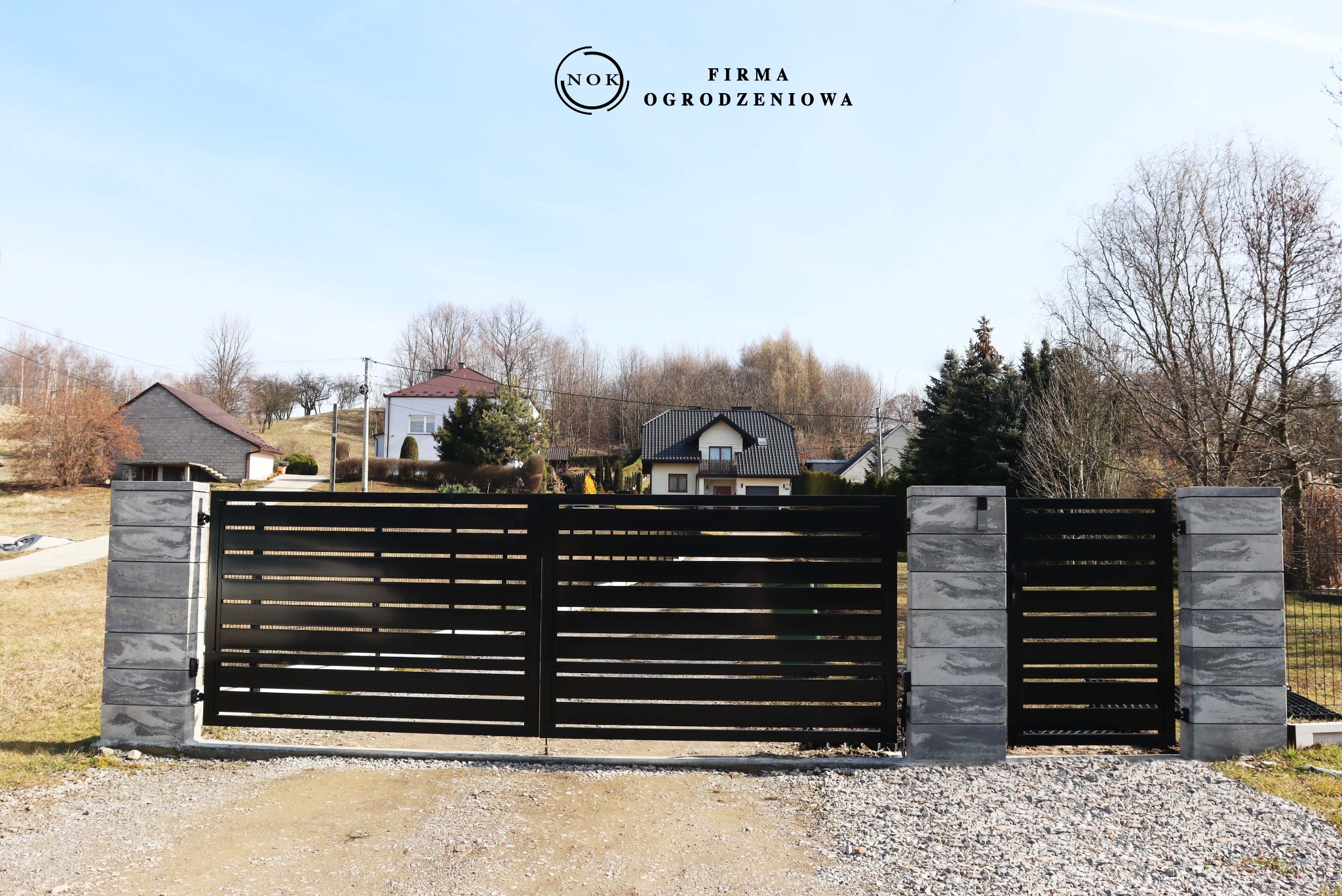 Czarna, dwuskrzydłowa brama palisadowa z furtką, zamontowana na słupkach z bloczków Joniec Roma Horizon, kolor marengo. Prześwit między profilami 2 cm.