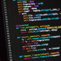 Ekran monitora z widocznym kodem źródłowym w języku Python, z wcięciami i kolorowaniem składni, wyświetlającym definicje klas i funkcji, w ciemnym otoczeniu.