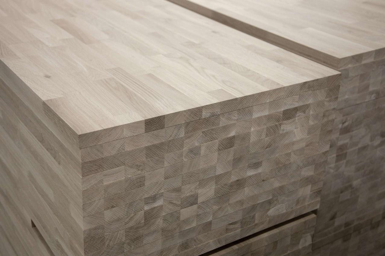 Stos jasnej, klejonej deski z widocznym usłojeniem drewna, ułożonej warstwami.