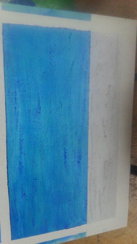 Świeżo pomalowana na niebiesko ściana, z widocznymi śladami pędzla i taśmą malarską zabezpieczającą krawędzie, obok fragment ściany przygotowywanej do malowania.