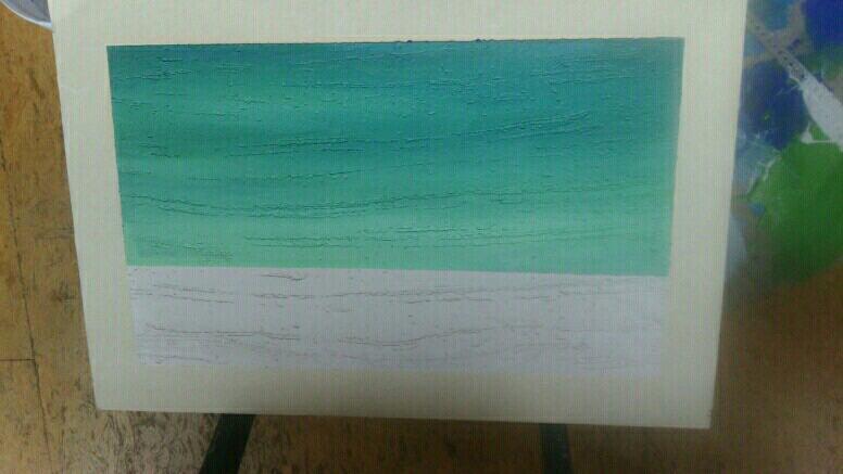 Świeżo pomalowana ściana z fakturą, górna część w odcieniach zieleni przechodzących w błękit, dolna część biała, widoczne niedoskonałości w fakturze i kryciu farby.