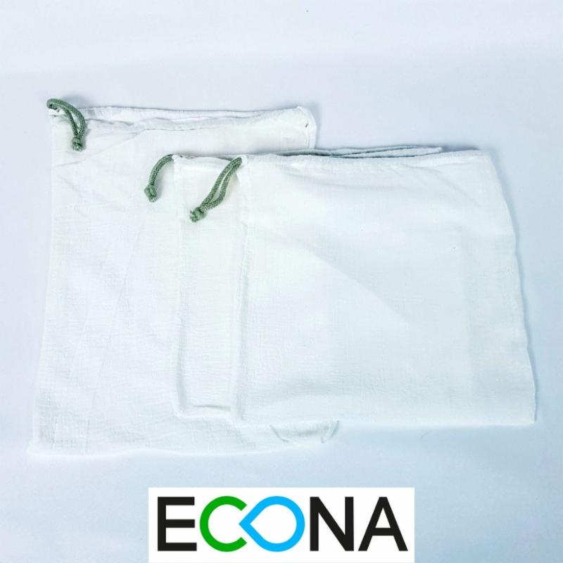 Dwie białe, bawełniane torby wielokrotnego użytku ze sznurkami w kolorze zielonym, widoczne logo firmy ECONA w dolnej części zdjęcia.