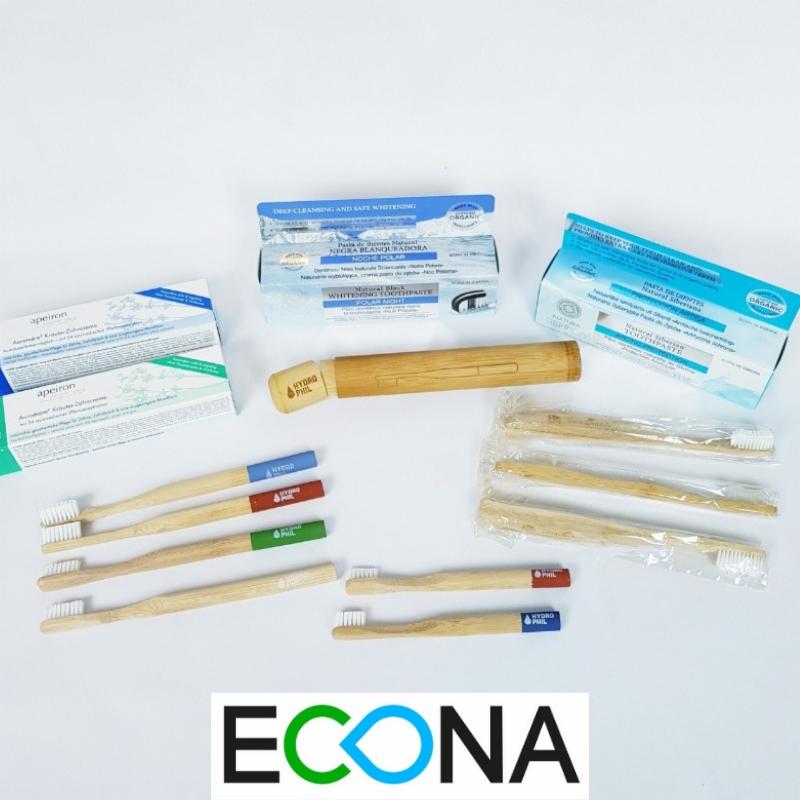 Zestaw ekologicznych środków do higieny jamy ustnej: pasty do zębów w kartonowych opakowaniach, bambusowe szczoteczki do zębów z kolorowymi końcówkami, bambusowe etui na szczoteczkę, logo ECONA...