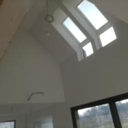 Bud-Tynk - Poddasze po remoncie w Police z oknami dachowymi i świeżo wyszpachlowanymi ścianami, widoczne przewody elektryczne.
