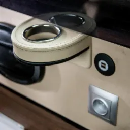 Wnętrze luksusowego busa: beżowa tapicerka, skórzany uchwyt na kubek z chromowanym wykończeniem, gniazdko elektryczne i port USB.