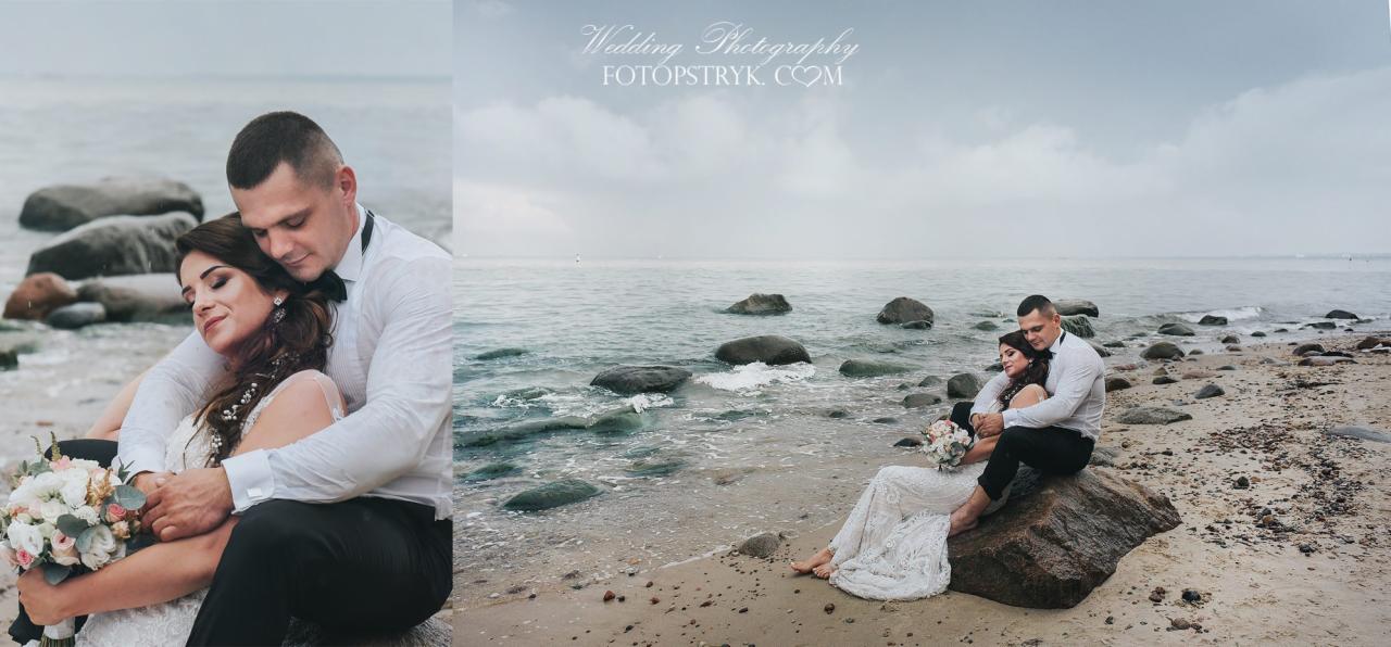 Para młoda w objęciach, siedząca na kamieniu na plaży; w tle morze i pochmurne niebo.