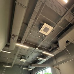 BUDLEP SPÓŁKA Z OGRANICZONĄ ODPOWIEDZIALNOŚCIĄ - Sufit biurowy w Świętochłowicach z zamontowanymi panelami klimatyzacyjnymi, oświetleniem liniowym i instalacjami podwieszonymi na szynach. Widok z dołu.