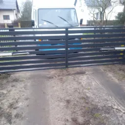 Szara, pozioma brama wjazdowa z automatyką na posesji, z widocznym samochodem dostawczym w tle, z perspektywy lekko z dołu.