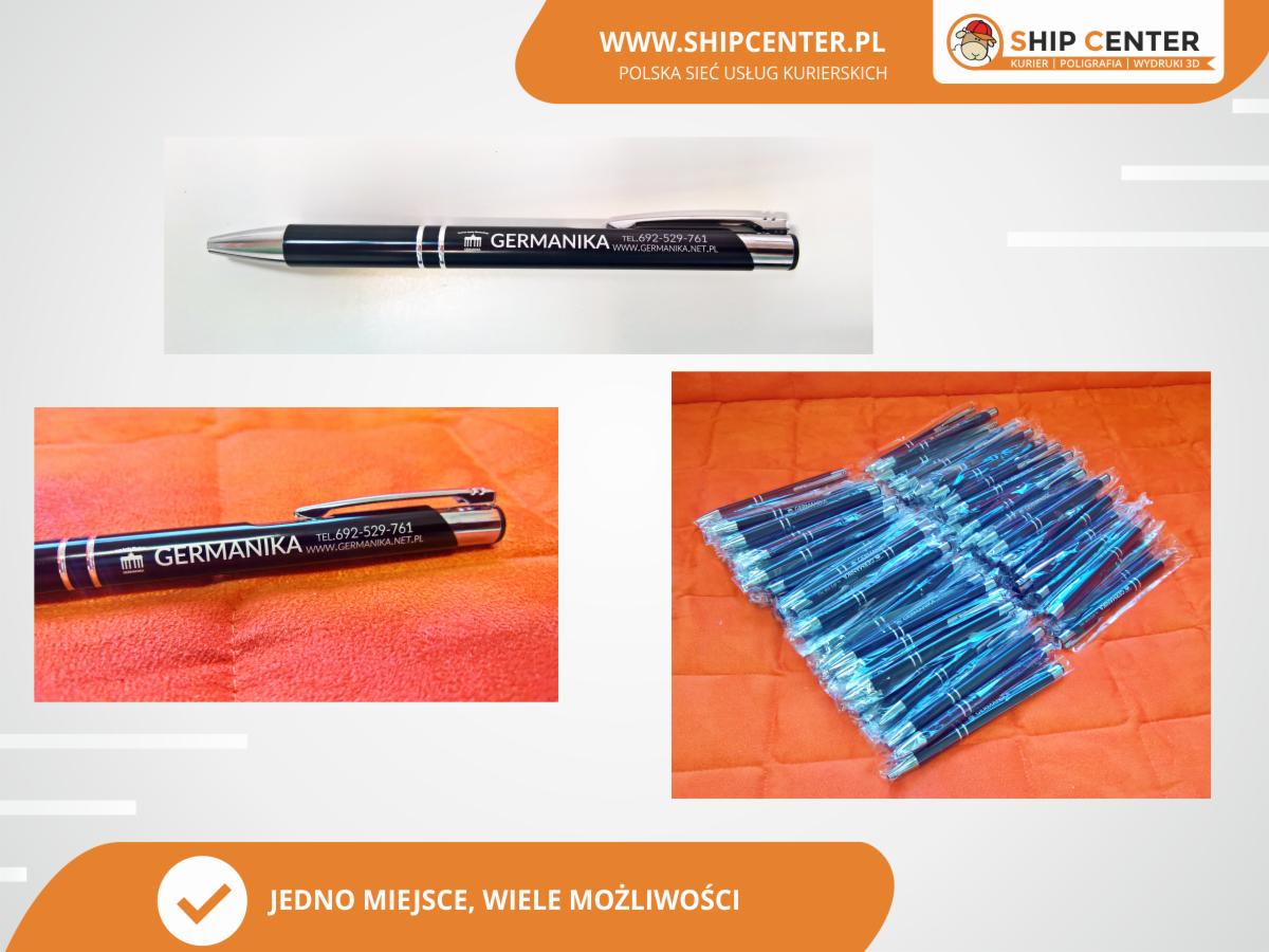 Długopisy z nadrukiem logo firmy GERMANIKA, część zapakowana w folię, leżące na pomarańczowym tle