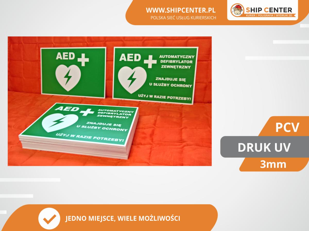 Stos naklejek i dwa pojedyncze znaki informacyjne AED z zielonym tłem, białym napisem i symbolem serca z błyskawicą, wykonane w technologii druku UV na PCV o grubości 3mm.