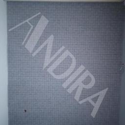 ANDIRA - Ściana pokryta szarą tapetą imitującą mozaikę z małych kwadratów; widoczny fragment podłogi i listwy sufitowej; na tapecie naniesiony jasny, ukośny napis 'ANDIRA' jako znak wodny.