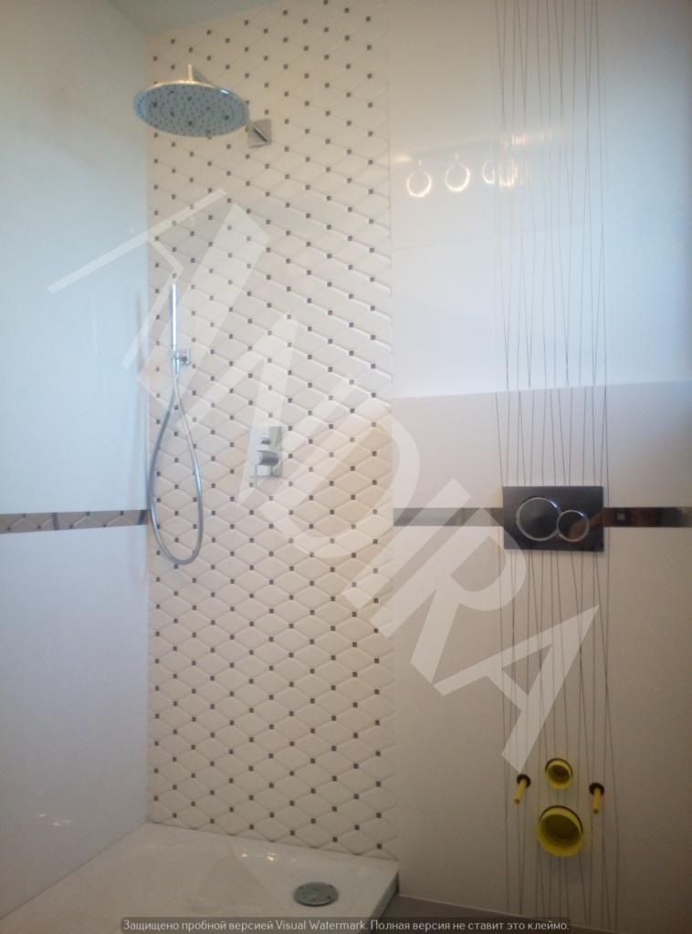 Wykończona kabina prysznicowa z mozaiką w romby, chromowaną armaturą i odpływem liniowym, widoczne przyłącza do toalety podtynkowej z dekoracyjnymi sznurkami.