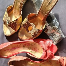 Hubert K. - Używane złote sandały Stylites z ozdobami i czerwone baleriny Letizia Ferrari z kwiatowym wzorem wewnątrz, leżące na ciemnym tle. Dodatkowo ozdoba w opakowaniu.
