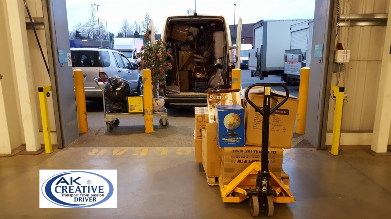 Załadunek busa wypełnionego kartonami i meblami, paleta z paczkami na wózku paletowym przed rampą, w tle widać dekoracyjną roślinę doniczkową i wózek z workami na śmieci.