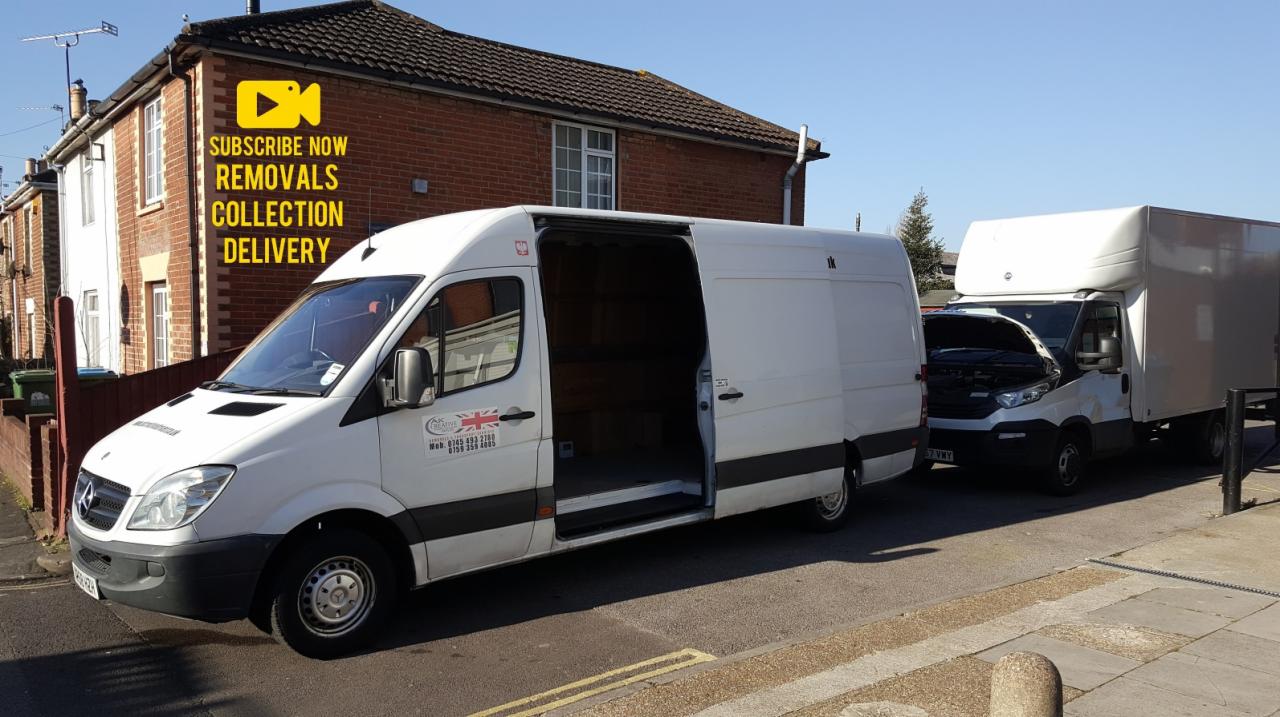 Dwa białe busy transportowe zaparkowane na ulicy przed budynkiem mieszkalnym; jeden z otwartymi drzwiami bocznymi, drugi z podniesioną maską silnika.