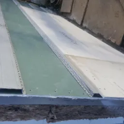 Montaż płyt Aquapanel na elewacji budynku, widoczne profile metalowe i warstwa izolacji z wełny mineralnej.