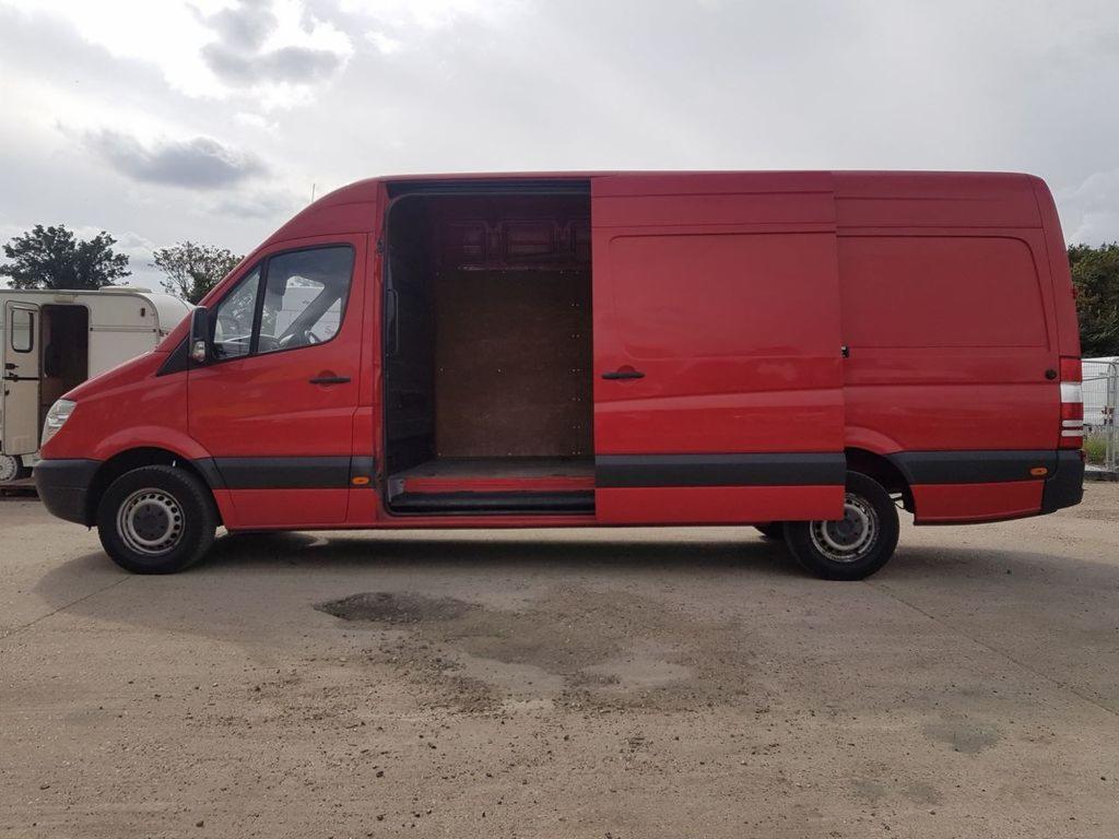 Czerwony bus dostawczy z otwartymi drzwiami bocznymi, widok z boku, pusta przestrzeń ładunkowa z drewnianą podłogą.