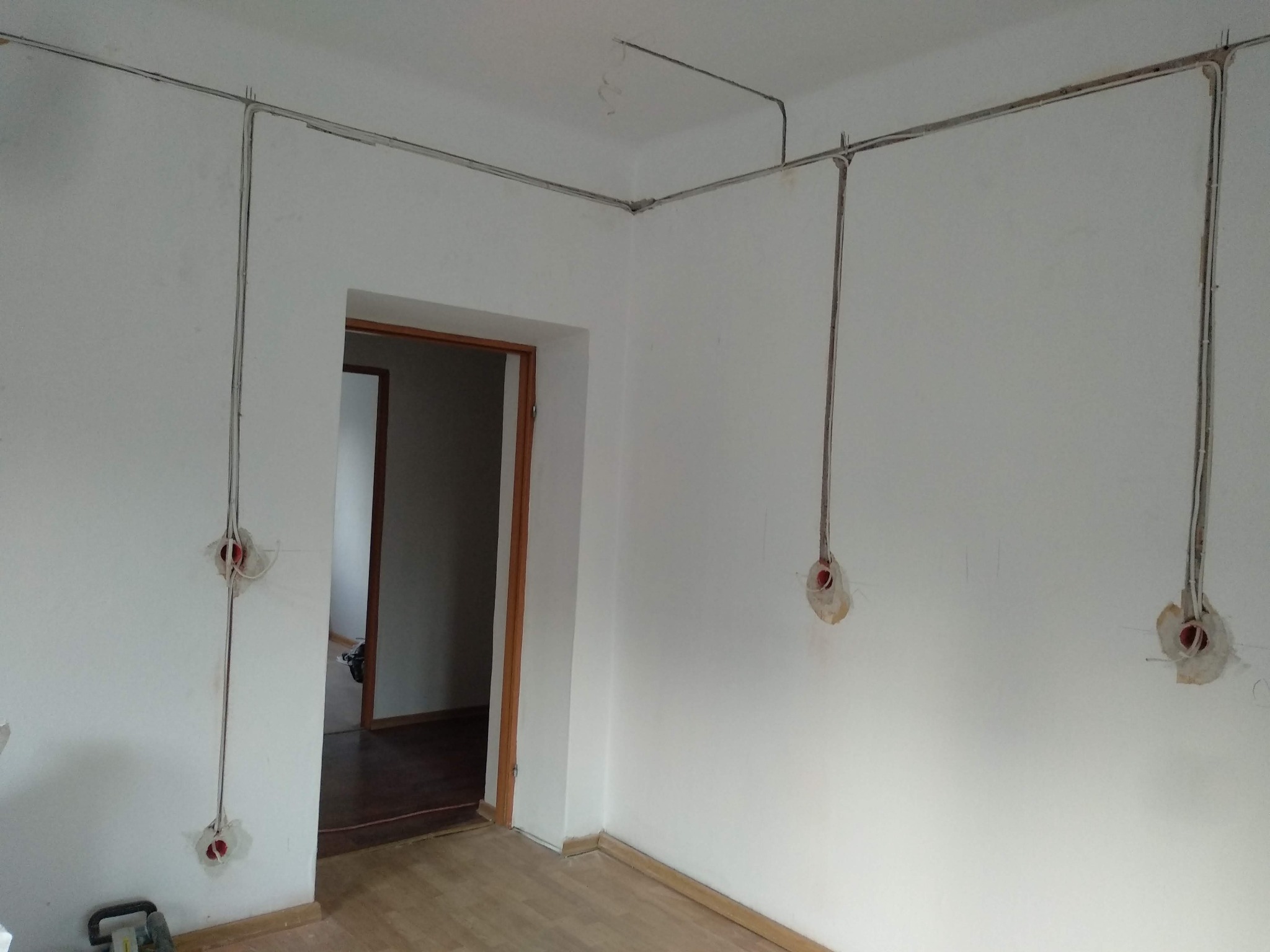 Wewnętrzne okablowanie elektryczne w trakcie instalacji w nowym budynku, widoczne kable prowadzone po ścianach i suficie, przygotowane otwory pod gniazdka.