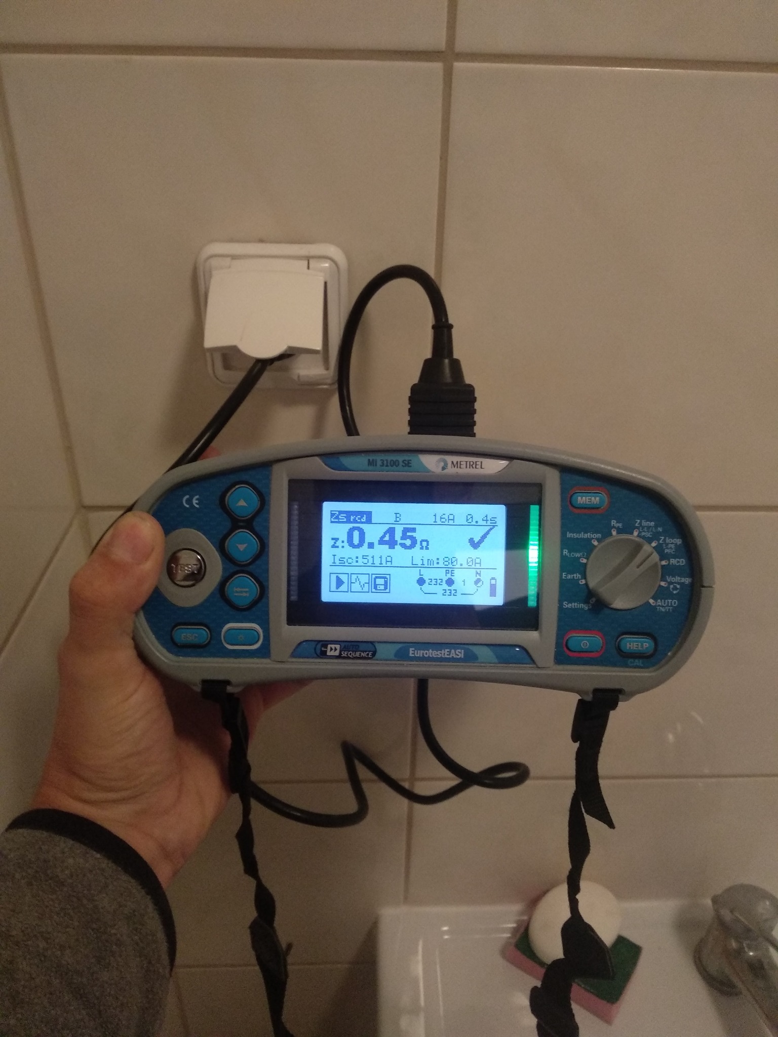 Pomiar impedancji pętli zwarcia w gniazdku elektrycznym za pomocą miernika EurotestEASI MI 3100 SE, wyświetlający wynik 0.45 oma.