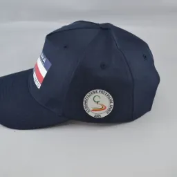 Granatowa czapka z daszkiem z haftowanym logo 'Stowarzyszenie Przyjaciół Skały' oraz flagą Polski, leżąca na jasnym tle.