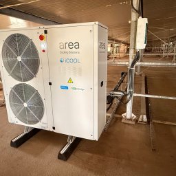 JAMRÓZ Nowoczesne Technologie - Biała jednostka klimatyzacyjna Area Cooling Solutions iCOOL z dwoma wentylatorami, zamontowana w hali produkcyjnej, widok z boku, kable zasilające.