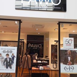 JAMRÓZ Nowoczesne Technologie - Elegancki salon odzieżowy Pawo z przeszkloną witryną prezentującą kolekcję garniturów i koszul. Widoczne plakaty promocyjne i oświetlenie sufitowe.