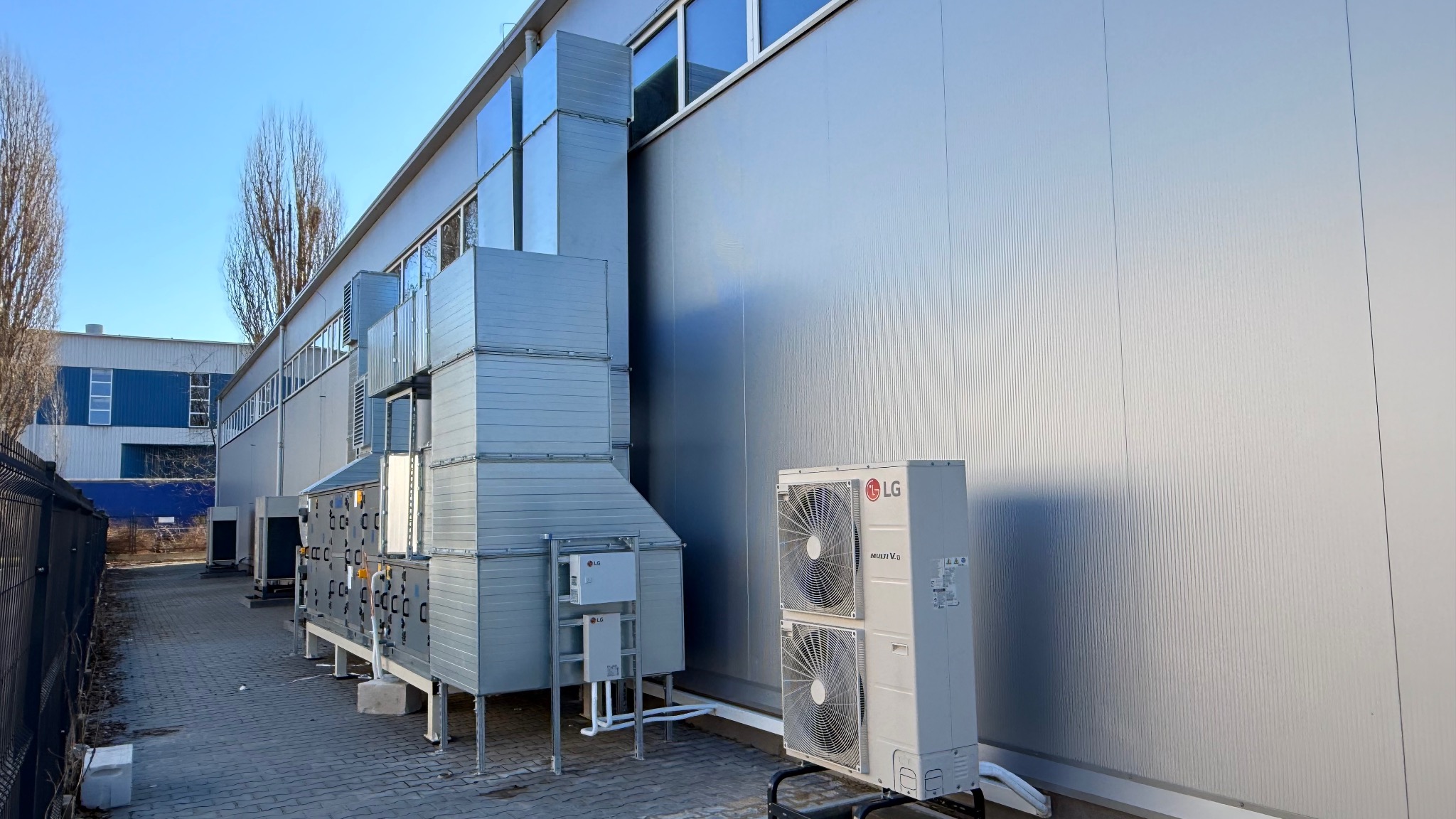 Instalacja klimatyzacji przemysłowej LG Multi V 8 na zewnątrz budynku. Widoczne jednostki zewnętrzne, kanały wentylacyjne i skrzynki sterownicze.