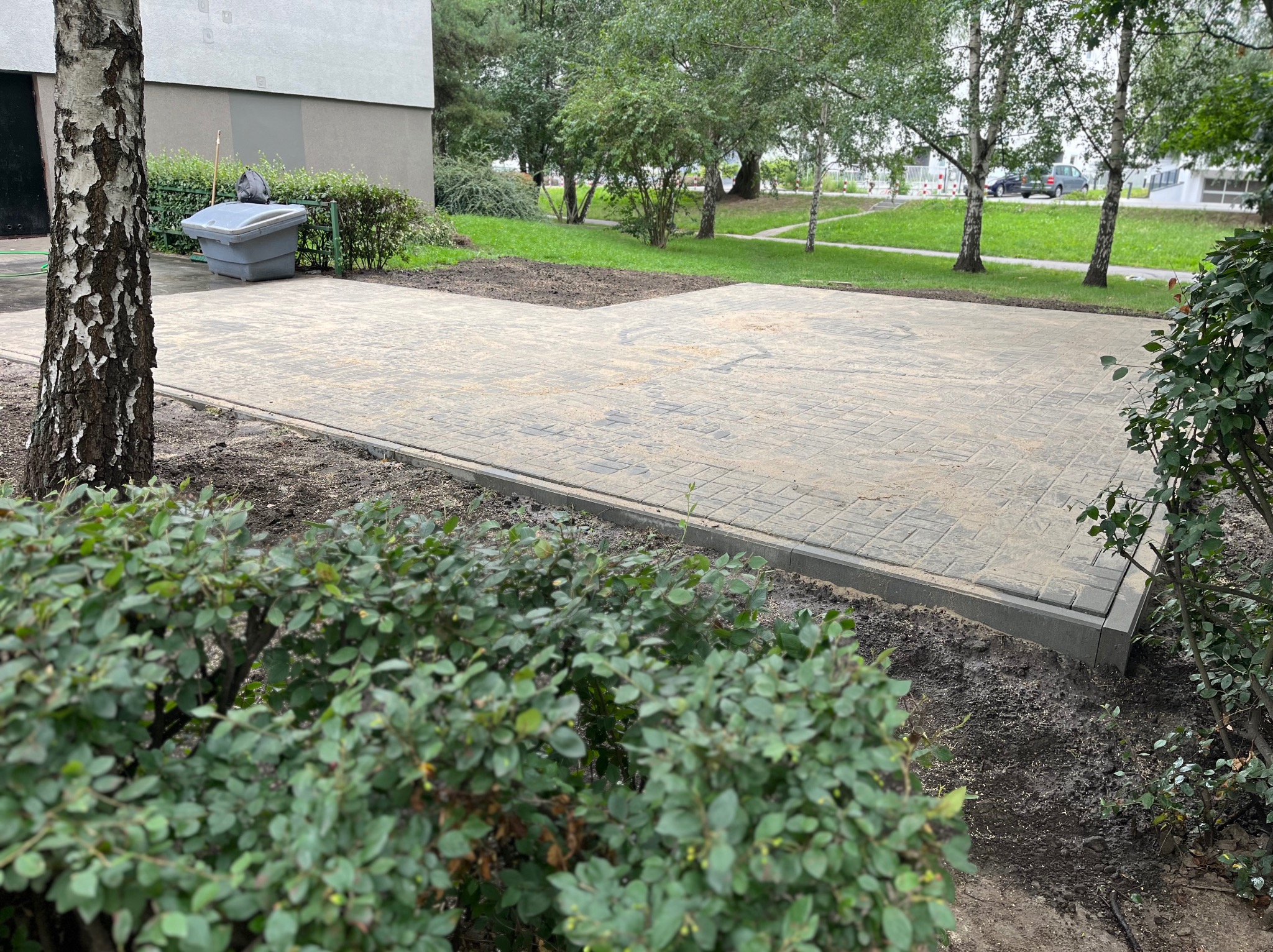 Ułożona kostka brukowa w Żyrardowie. Widok na świeżo wybrukowany plac z szarej kostki, obrzeża i przygotowane rabaty. Praca wykonana z dbałością o detale.