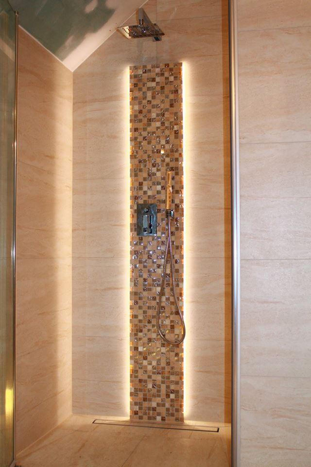 Beżowa kabina prysznicowa z mozaiką i podświetleniem LED, widoczny deszczownica i bateria.