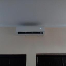 Coldmark - Biały klimatyzator ścienny zamontowany nad ciemnymi drzwiami, wyświetlający temperaturę 17 stopni Celsjusza na jasnej ścianie.