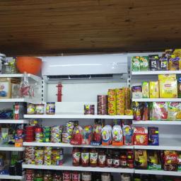 Coldmark - Biały klimatyzator ścienny zamontowany w sklepie spożywczym, widoczny nad półkami z różnorodnymi produktami spożywczymi.