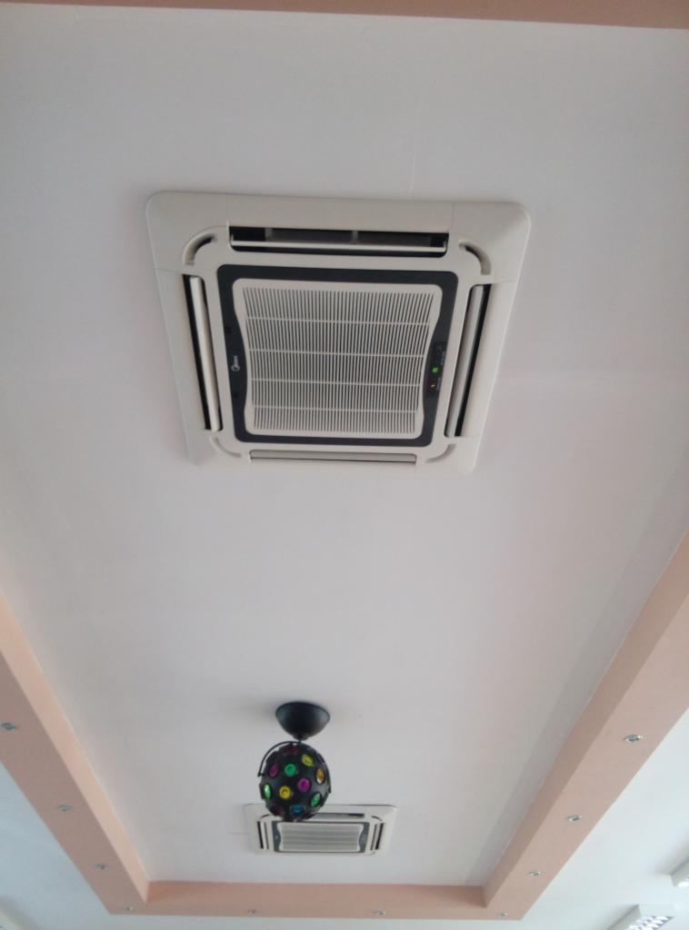 Sufit z dwoma klimatyzatorami kasetonowymi, jeden biały z czarną obwódką, drugi podwieszony pod kulą dyskotekową, oświetlenie punktowe na listwie sufitowej.