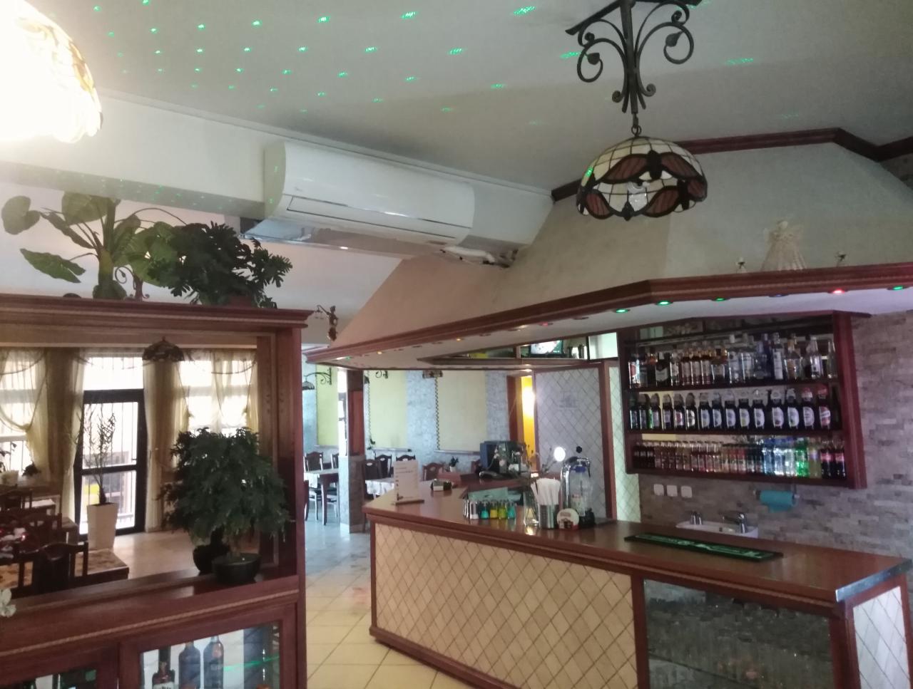 Wnętrze restauracji z zainstalowaną klimatyzacją kasetonową pod sufitem, widoczny bar, stoliki i oświetlenie dekoracyjne.
