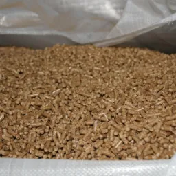 Wnętrze worka wypełnionego jasnobrązowym pelletem drzewnym o cylindrycznym kształcie.