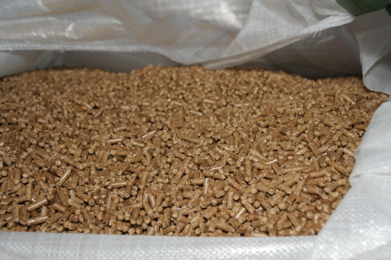 Wnętrze worka wypełnionego jasnobrązowym pelletem drzewnym o cylindrycznym kształcie.