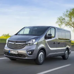 Szara furgonetka Opel Vivaro z przyciemnionymi szybami, jadąca po autostradzie w słoneczny dzień.