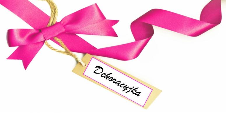 Różowa wstążka z kokardą i etykietą z napisem 'Dekoracyjka' na białym tle.