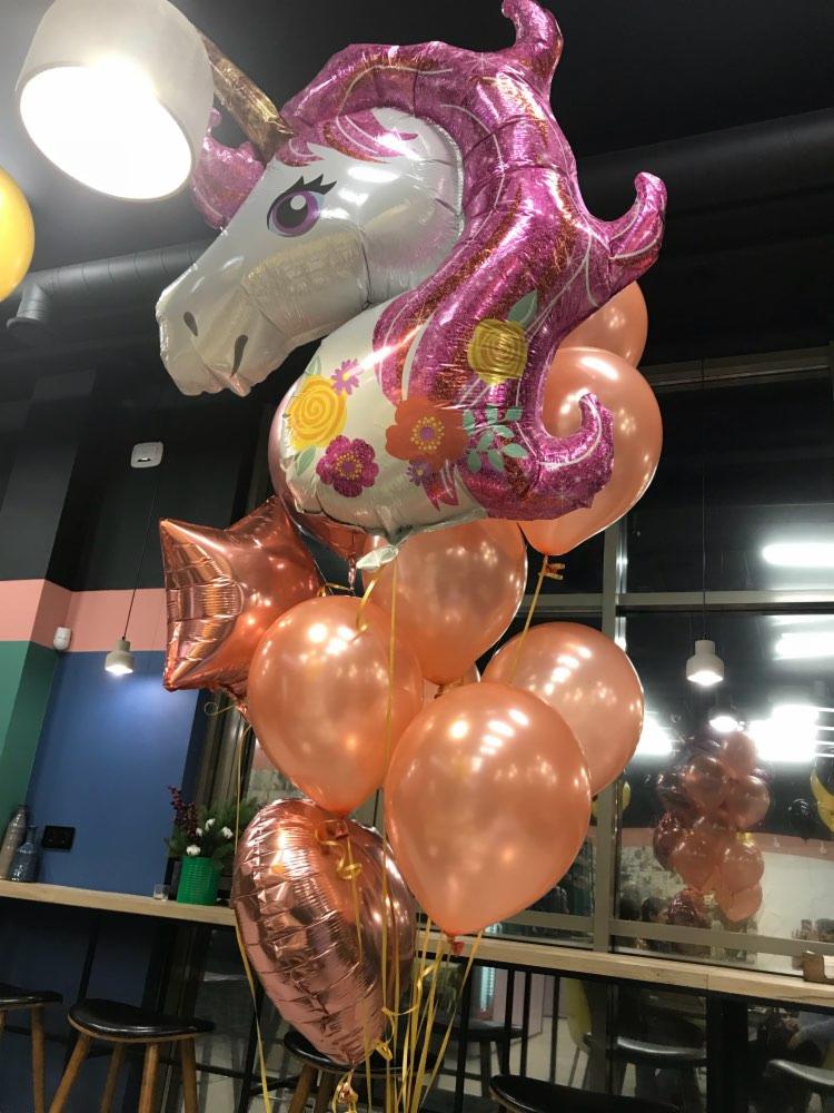 Balon foliowy w kształcie głowy jednorożca z różową grzywą i kwiatami, otoczony bukietem brzoskwiniowych balonów, dekoracja imprezowa.