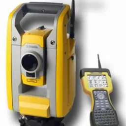 Żółto-szary tachimetr Trimble z anteną i kontrolerem w kolorze żółtym na jasnym tle.