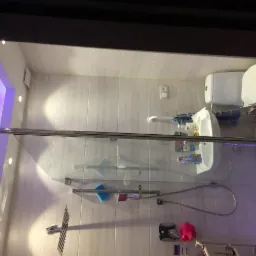 Wyremontowana łazienka z kabiną prysznicową, umywalką i toaletą w Nadarzynie, oświetlona fioletowym światłem LED.