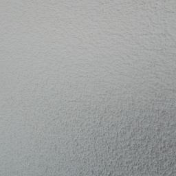 Kontrast - Szara ściana pokryta tynkiem strukturalnym typu baranek, z delikatnym cieniowaniem w lewym dolnym rogu.