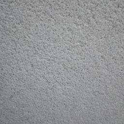 Kontrast - Zbliżenie na szorstką, jasnoszarą strukturę powierzchni, przypominającą świeżo nałożoną warstwę wykończeniową z widocznymi drobnymi nierównościami.